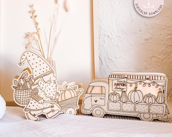 May include: Wooden laser-cut fall decor featuring a gnome with a basket of pumpkins and a pumpkin cart. A pumpkin truck with the text "Fresh Pumpkins Today" is also included. The decor is made of light-colored wood and is set against a neutral background.