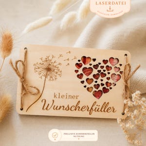 Op de afbeelding: Houten plaat met een paardenbloem- en hartontwerp. Het hart bestaat uit kleinere harten in rood- en bruintinten. De tekst "kleiner Wunscherfüller" is gegraveerd. De plaat is vastgebonden met touw.