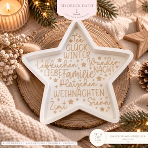 May include: A white star-shaped tray featuring gold-colored German text including words like Tee, Gluck, Winter, Lebkuchen, Wunder, Nacht, Liebe, Familie, Platzchen, Weihnachten, Zimt, and Stern, interspersed with small gold star icons throughout.