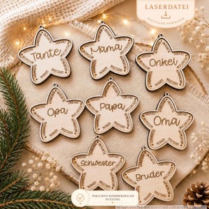 Puede incluir: Ocho adornos de madera en forma de estrella con texto en alemán grabado. Cada estrella muestra un título familiar central como Tante, Mama, Onkel, Opa, Papa, Oma, Schwester o Bruder, rodeado de palabras descriptivas grabadas.