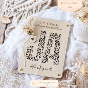 Könnte beinhalten: Eine rechteckige Holzplatte in hellem Farbton mit lasergeschnittenen Blumenmustern, die die Buchstaben JA bilden. Der Text lautet Ein kleiner Wunscherfüller und zur Hochzeit. Ein kleiner Trockenblumenstrauß ist mit weißer Schnur befestigt.