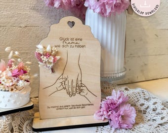 May include: Wooden sign with a heart-shaped cutout at the top. The sign has a quote about the happiness of having a mother, along with a drawing of hands holding each other. The sign is on a stand and has a light wood finish.