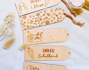 Puede incluir: Cinco marcapáginas de madera con diferentes diseños. Los marcapáginas están grabados con varias ilustraciones y textos con temática escolar, incluyendo una mochila, un estuche de lápices, un cono y las palabras "Du bist 1. Klasse" y "Endlich Schulkind".