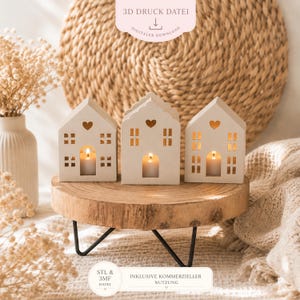May include: Three cream-coloured ceramic house-shaped candle holders with heart cutouts and window details, each with a lit candle. They are on a wooden slice atop a black metal stand. The image includes text that says "3D Druck Datei" and "Digitaler Download".