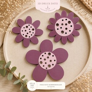 May include: Three flower-shaped coasters in shades of purple and pink are arranged on a light-coloured tray. The coasters have a petal design with a circular centre featuring small, evenly spaced holes. The image includes text that reads "3D Druck Datei" and "Digitaler Download".