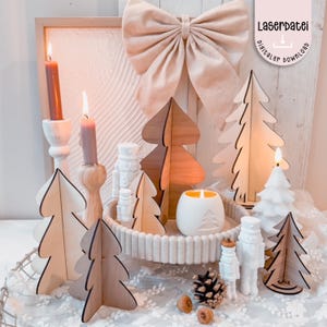 Könnte beinhalten: Eine festliche Weihnachtsdekoration mit Weihnachtsbäumen aus Holz, Kerzen und dekorativen Elementen. Die Anordnung umfasst brennende Kerzen in verschiedenen Haltern, einen weißen Kerzenhalter aus Keramik und eine große Schleife. Der Text "Laserdatei digitaler download" ist sichtbar.
