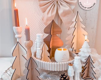 May include: A festive holiday display featuring wooden Christmas trees, candles, and decorative elements. The arrangement includes lit candles in various holders, a white ceramic candle holder, and a large bow. The text "Laserdatei digitaler download" is visible.
