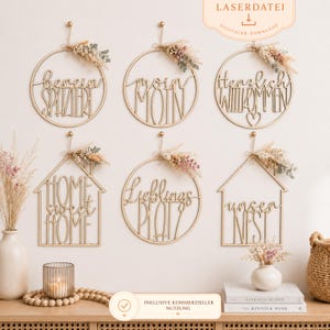 Puede incluir: Seis adornos de pared de madera con letras escritas y arreglos florales secos. Las frases incluyen "herein spaziert", "moin moin", "herzlich willkommen", "home sweet home", "lieblings platz" y "unser nest". Cada pieza est&aacute; suspendida por un gancho dorado.