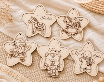 May include: Five star-shaped wooden ornaments featuring laser-engraved designs including a Dala horse, a rocking horse, Santa Claus, a bear wearing a scarf, and a gingerbread person. Each ornament includes a small hole at the top for hanging.