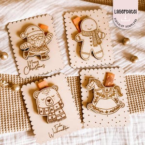 May include: Four wooden Christmas-themed gift tags. Each tag features a laser-cut design: Santa Claus, a gingerbread man, a bear, and a rocking horse. The tags have scalloped edges and include the phrases "Merry Christmas" and "Frohe Weihnachten".