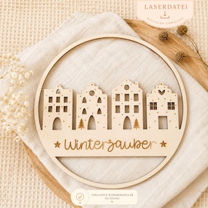 Può includere: Decorazione circolare in legno chiaro, tagliata al laser, raffigurante un villaggio invernale. Il design include case stilizzate, alberi e la scritta "Winterzauber". Ideale per un'atmosfera invernale.