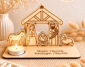 May include: A wooden nativity scene with a candle. The scene includes a stable, Mary, Joseph, baby Jesus, a donkey, and a sheep. The base has the words "Stille Nacht, heilige Nacht" engraved. A small candle is lit in front of the scene.