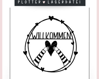 May include: Black and white design of a heart held by two hands with the word "Willkommen" above it. The design is surrounded by a circle of hearts.
