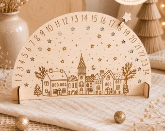 May include: A semi-circular wooden advent calendar featuring a laser-engraved winter village scene with houses, a church, and trees. The arch is numbered from 1 to 24, decorated with small star cutouts and a movable star marker for tracking days.