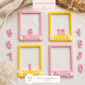 Peut inclure: Quatre cadres rectangulaires roses et jaunes, conçus comme des porte-photos. Chaque cadre porte le mot allemand "Monate" ou "Monat" avec des cœurs ou des fleurs décoratifs. Inclut des chiffres séparés de 0 à 9 pour le suivi de l'âge.