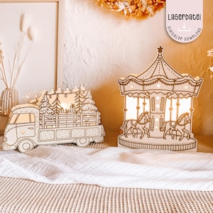 Puede incluir: Dos decoraciones de madera iluminadas: una camioneta vintage que transporta árboles de Navidad y un carrusel con caballos. La camioneta y el carrusel están hechos de madera de color claro con intrincados diseños recortados. El carrusel tiene una estrella en la parte superior y el texto "Laserdatei digitaler download".