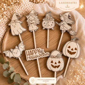 Op de afbeelding: Houten Halloween-decoraties, waaronder een spook, heks, ketel, vleermuis, pompoen en een bord met "Happy Halloween". De decoraties zijn lichtbruin en hebben een rustieke, handgemaakte uitstraling. Ze liggen op een houten dienblad.