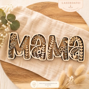 Könnte beinhalten: Holzschild "Mama" mit floralen Ausschnitten. Die Buchstaben sind geschichtet, wodurch ein 3D-Effekt entsteht. Das Schild ist hellbraun mit dunkleren Kanten, und die floralen Details sind filigran. Das Schild befindet sich auf einer neutralfarbenen Oberfläche.
