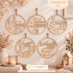 Op de afbeelding: Vijf ronde houten wandhangers met lasergesneden ontwerpen en Duitse tekst. De ontwerpen bevatten een hert met 'Frohes Fest', een kabouter met 'Schöne Weihnachten', een boom met 'Winterzeit', een huis met 'Hygge Zeit' en een auto met 'Weihnachtszauber'.