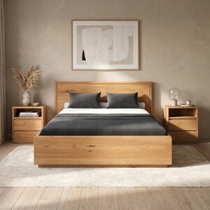 Op de afbeelding: Een bedframe van licht eikenhout met een hoog hoofdeinde, voorzien van een donkergrijs matras, twee bijpassende donkergrijze rechthoekige kussens en twee nachtkastjes van licht eikenhout met elk twee lades aan weerszijden van het bed.