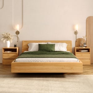 Könnte beinhalten: Ein modernes Schlafzimmer-Set mit einem hellen Holzbetttisch, weißer Bettwäsche und einer grünen Decke. Zwei passende Nachttische flankieren das Bett, jeweils mit einer Lampe und dekorativen Gegenständen. Der Raum hat eine neutrale Farbpalette.