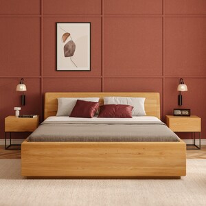 Könnte beinhalten: Ein modernes Holzbett mit hellem Holzfinish und minimalistischem Design. Das Bett ist mit einer grauen Bettdecke und Kissen ausgestattet. Zwei Nachttische mit Lampen flankieren das Bett. Ein gerahmtes abstraktes Kunstwerk hängt über dem Bett.