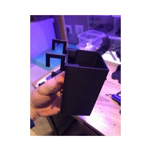 May include: A black 3D printed plastic container with a rectangular shape and two small handles on the side.
