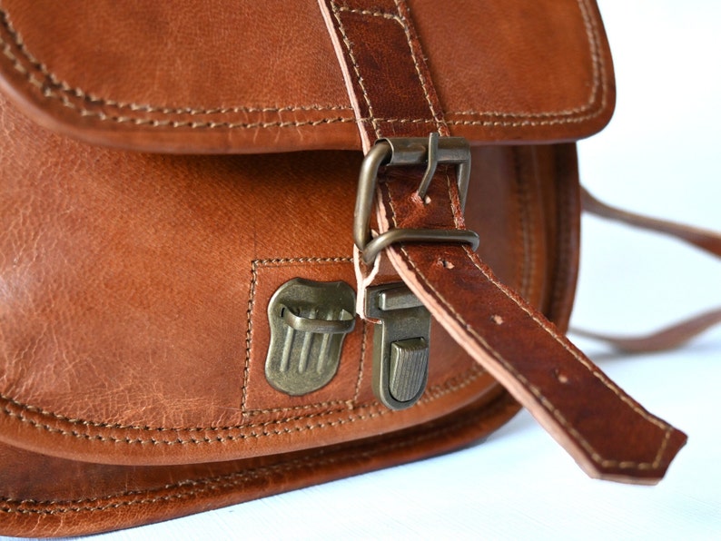 Handgefertigte Umhängetasche aus 100% Naturleder. Halbrunde From mit Druckschnallen-Verschluss in Vintage Optik. Tragriemen in der Länge verstellbar. Nahaufnahme der Druckschnalle