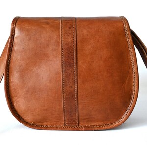 Handgefertigte Umhängetasche aus 100% Naturleder. Halbrunde From mit Druckschnallen-Verschluss in Vintage Optik. Tragriemen in der Länge verstellbar. Rückseite der Tasche vor weißem Hintergrund.