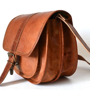 Handgefertigte Umhängetasche aus 100% Naturleder. Halbrunde From mit Druckschnallen-Verschluss in Vintage Optik. Tragriemen in der Länge verstellbar. Seitenansicht mit weißem Hintergrund.