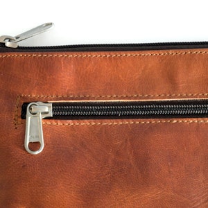 Fair produzierter Lederbeutel in Braun, Detailaufnahme der Lederstruktur und des Reißverschlusses.