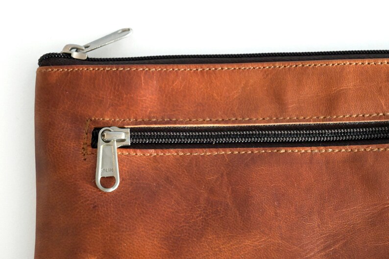 Fair produzierter Lederbeutel in Braun, Detailaufnahme der Lederstruktur und des Reißverschlusses.