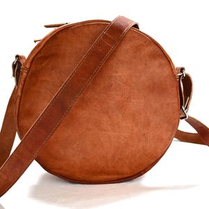 Handgenähte runde Tasche aus natürlich gegerbtem Leder. Trageriemen der Umhängetasche ist der Länge verstellbar. 
Rückseite der Tasche.