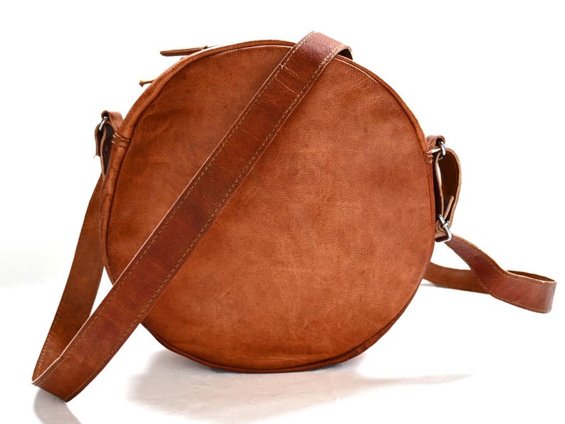 Handgenähte runde Tasche aus natürlich gegerbtem Leder. Trageriemen der Umhängetasche ist der Länge verstellbar. 
Rückseite der Tasche.