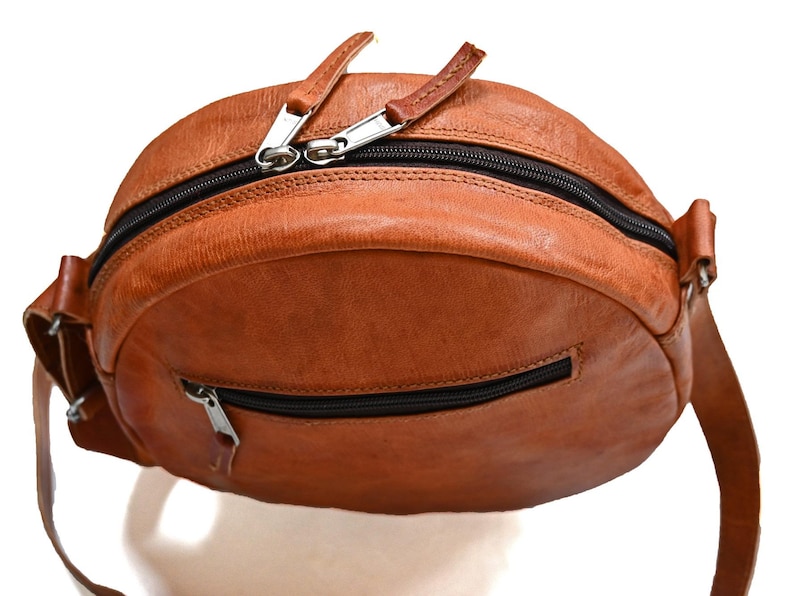 Handgenähte runde Tasche aus natürlich gegerbtem Leder. Trageriemen der Umhängetasche ist der Länge verstellbar. 
Ansicht der Tasche von Oben.