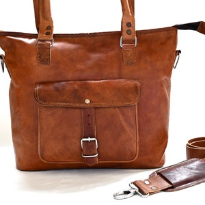 May include: A brown leather tote bag with a large front pocket and a buckle closure. The bag has a detachable shoulder strap.