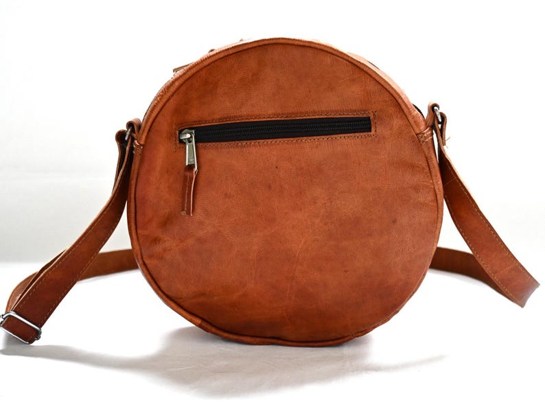 Handgenähte runde Tasche aus natürlich gegerbtem Leder. Trageriemen der Umhängetasche ist der Länge verstellbar. 
Frontansicht der Tasche.