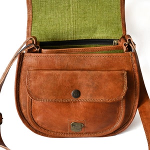 Handgefertigte Umhängetasche aus 100% Naturleder. Halbrunde From mit Druckschnallen-Verschluss in Vintage Optik. Tragriemen in der Länge verstellbar. Frontansicht der geöffneten Tasche vor weißem Hintergrund.