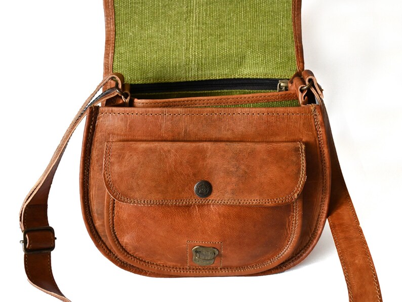 Handgefertigte Umhängetasche aus 100% Naturleder. Halbrunde From mit Druckschnallen-Verschluss in Vintage Optik. Tragriemen in der Länge verstellbar. Frontansicht der geöffneten Tasche vor weißem Hintergrund.