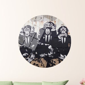 Puede incluir: Una pieza de arte de pared circular con una imagen en blanco y negro de tres chimpancés con trajes y cubriéndose los ojos, la boca y las orejas. Los chimpancés están representados en un estilo de graffiti.