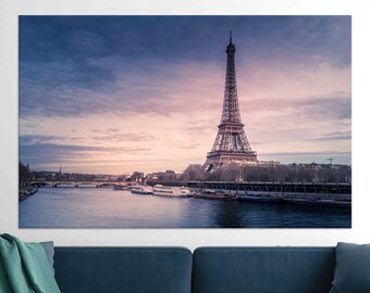 以下が含まれることがあります： フランスのパリにあるエッフェル塔のパノラマビュー。塔は街のランドマークであり、セーヌ川と他の建物に囲まれています。空は柔らかなピンクとパープルで、太陽は遠くで沈んでいます。