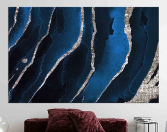 May include: Abstract art print with blue and silver watercolor-like paint. The silver paint is in a wavy, linear pattern on a dark blue background.