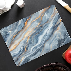 May include: Rectangular cutting board with a blue and gold marble design. The board features a swirling pattern of blue, gray, and gold veins. The board is made of a smooth, non-porous material, ideal for food preparation. The board is approximately 12 inches long and 8 inches wide.