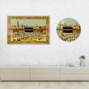 May include: Two framed prints depicting a religious scene with a central black structure, surrounded by a crowd of people. The rectangular print has a decorative border. The round print mirrors the scene. The prints are displayed on a white wall.