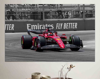 Könnte beinhalten: Ein leuchtend rotes Formel-1-Rennauto auf einer Rennstrecke. Es hat schwarze Reifen und Akzente. Das Logo Emirates FLY BETTER ist im Hintergrund zu sehen. Das Bild ist ein Leinwanddruck.