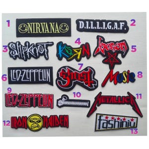 May include: A collection of thirteen embroidered fabric patches featuring various band logos and text designs including Nirvana, Slipknot, Led Zeppelin, Ghost, Metallica, Iron Maiden, and Fashiniu, each labelled with a pink number from one to thirteen.