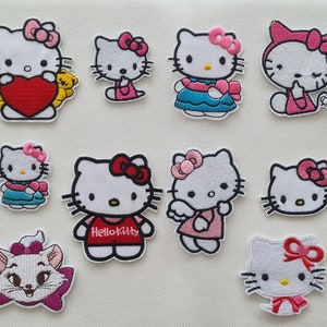 May include: A selection of embroidered Hello Kitty patches, showcasing the character in diverse poses and outfits. The patches feature Hello Kitty with bows, hearts, and floral details, in shades of pink, red, and blue. The patches are set against a white backdrop.