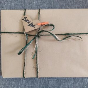 May include: A brown paper package tied with green and brown twine. A heart-shaped tag with the word "Besties" is attached to the package.