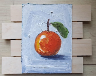 May include: Oil painting of a vibrant orange fruit with a green leaf, set against a light blue background. The artwork is mounted on a wooden frame, showcasing the textured brushstrokes and rich colors of the fruit.