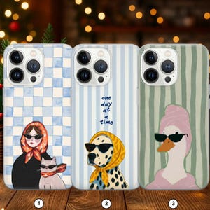Peut inclure: Trois coques de téléphone avec des motifs originaux. L'une représente une femme avec des lunettes de soleil et un chat, une autre un dalmatien avec des lunettes de soleil, et la dernière un canard avec une serviette rose et des lunettes de soleil.